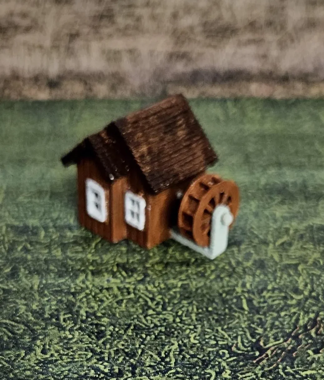 Angled view of N scale waterwheel with small building